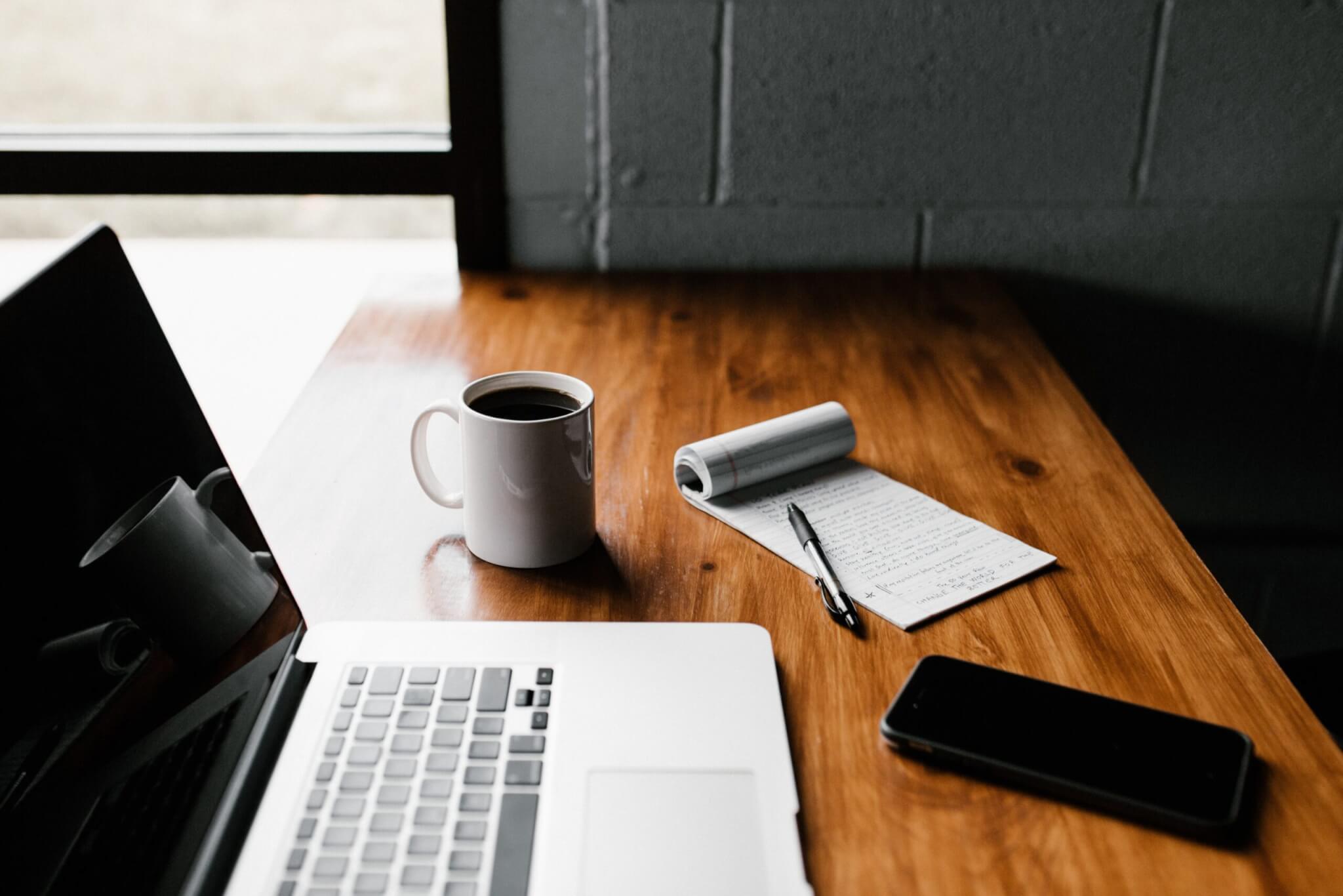 Taking Notes at Desk with Coffee and Laptop